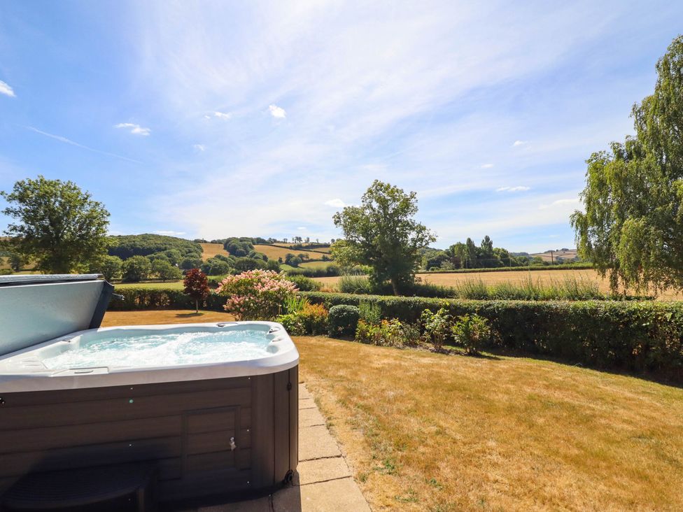 A garden with a hot tub and landscaped area at Pwll Glas in Trefeglwys