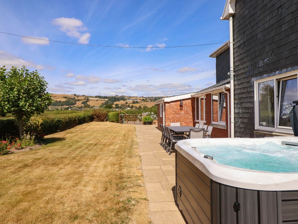 A garden with hot tub and dining area at Pwll Glas in Trefeglwys