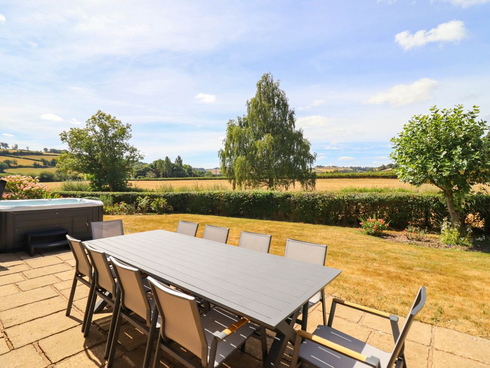 An outdoor dining area with a hot tub at Pwll Glas in Trefeglwys