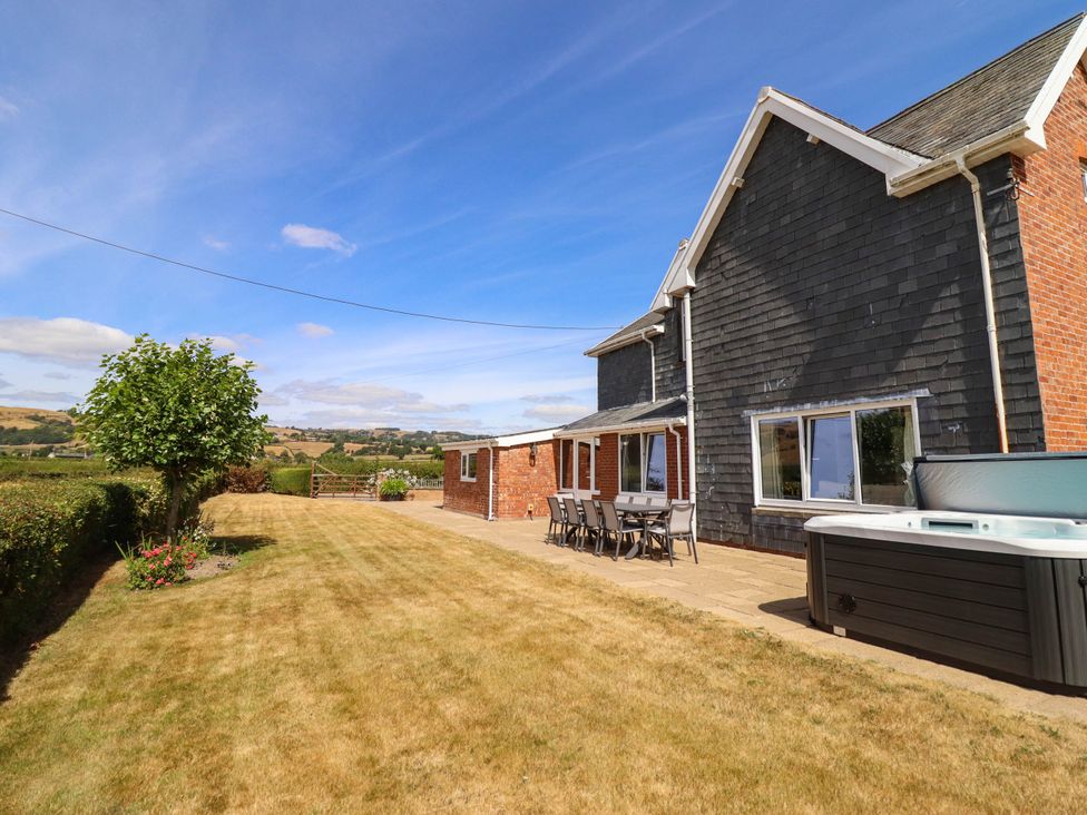 A house with patio furniture and a hot tub at Pwll Glas in Trefeglwys
