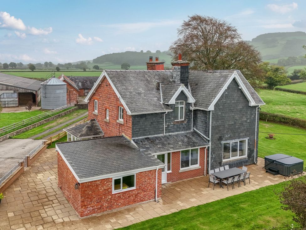 A house with a patio and table and chairs at Pwll Glas in Trefeglwys