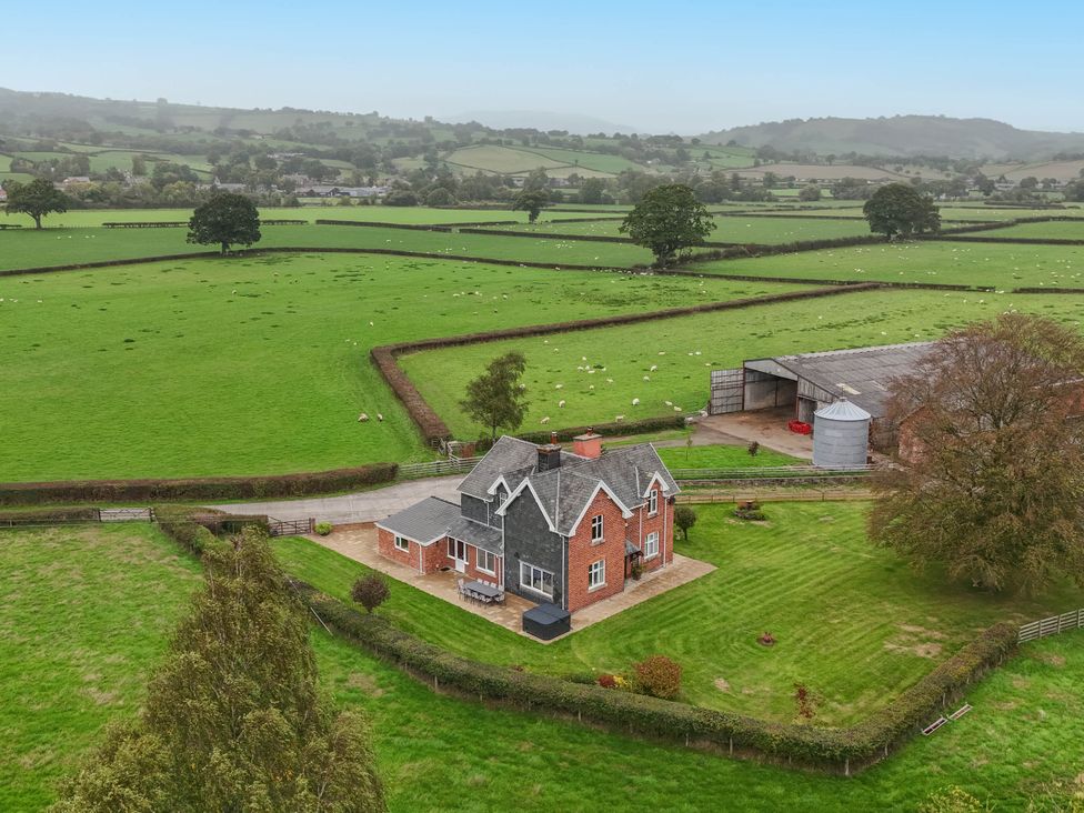 A farm with a house and barn in an open field at Pwll Glas, Trefeglwys