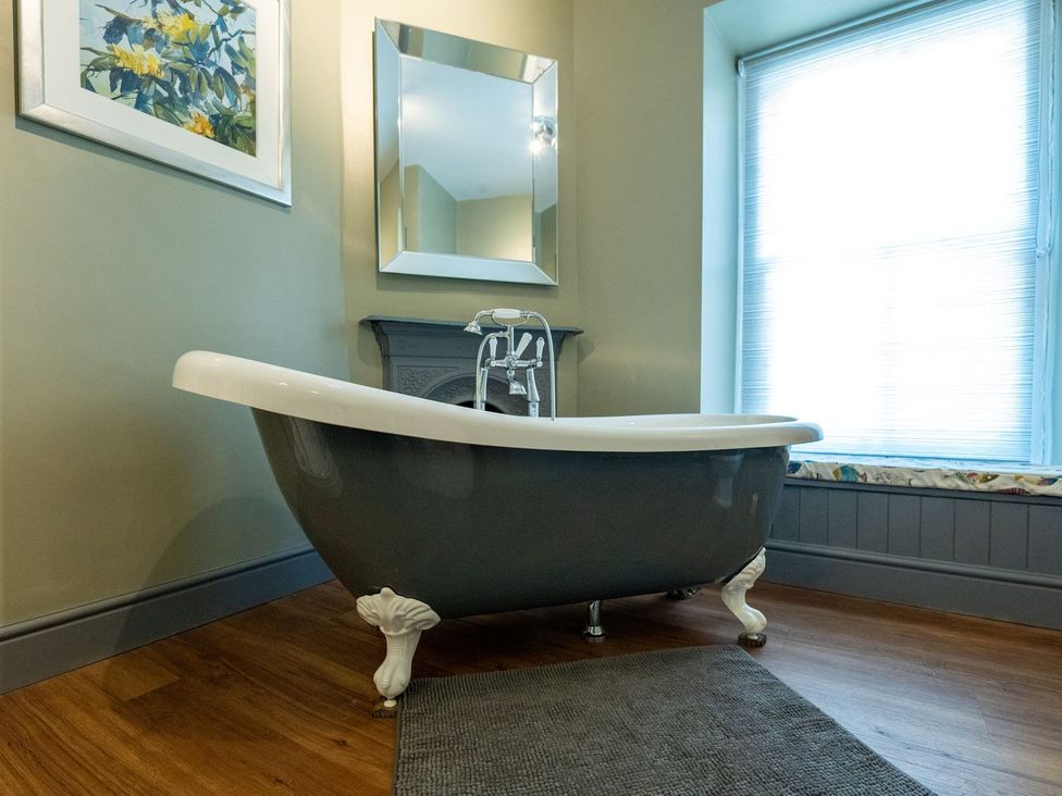A bathroom with a bathtub and a mirror at Gwynfryn House in Llanbedr