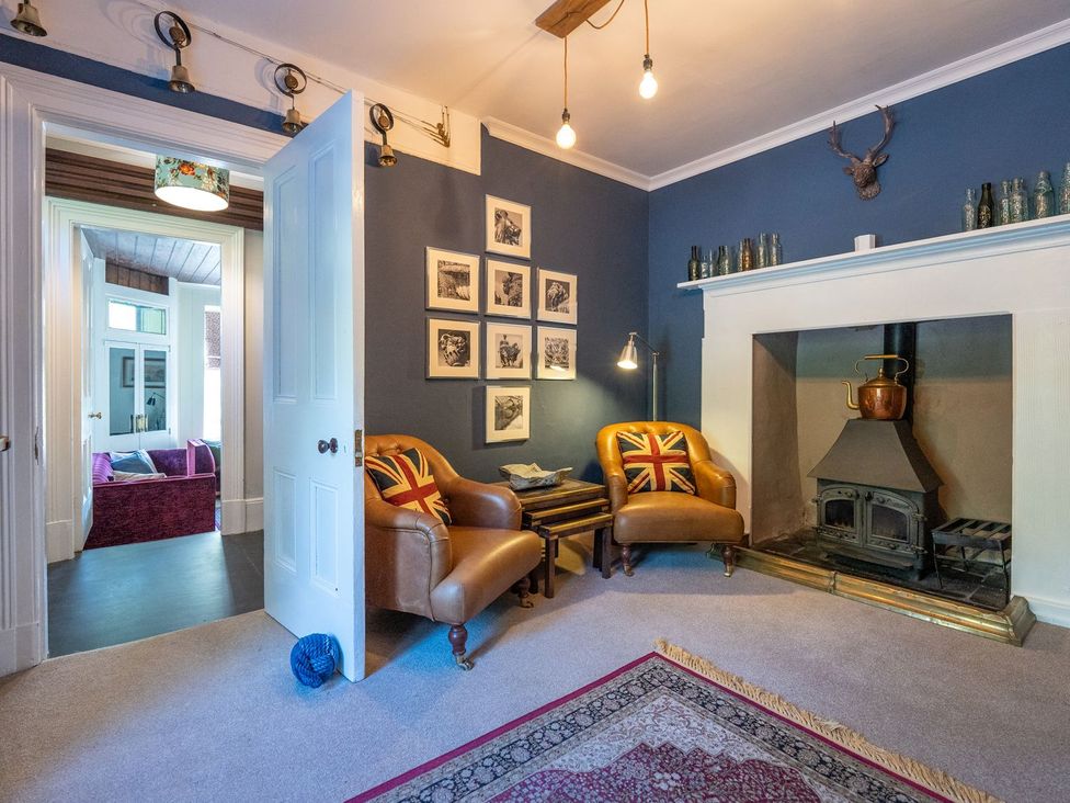A living room with a fireplace and armchairs at Gwynfryn House in Llanbedr