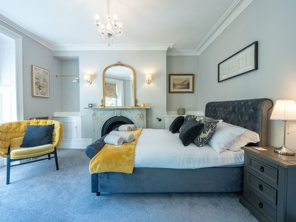 A bedroom with a bed, nightstand, and chair at Gwynfryn House in Llanbedr