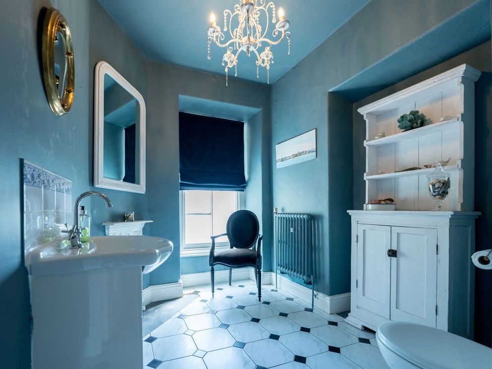 A bathroom with a sink, toilet, and cupboard at Gwynfryn House in Llanbedr