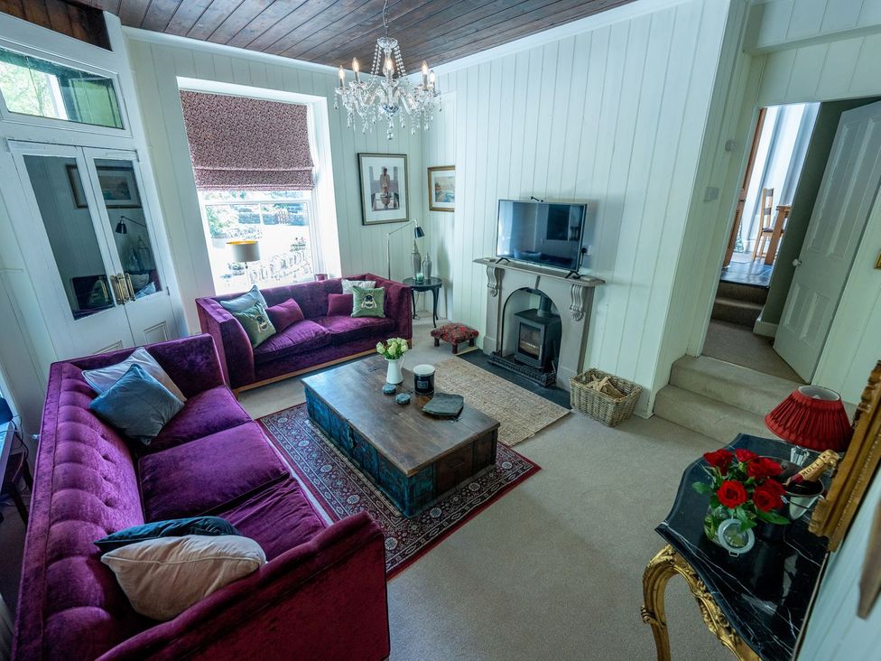 A living room with a TV, sofa, and coffee table at Gwynfryn House in Llanbedr
