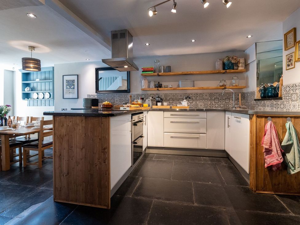 A kitchen with an island, shelves and dining table at Gwynfryn House in Llanbedr