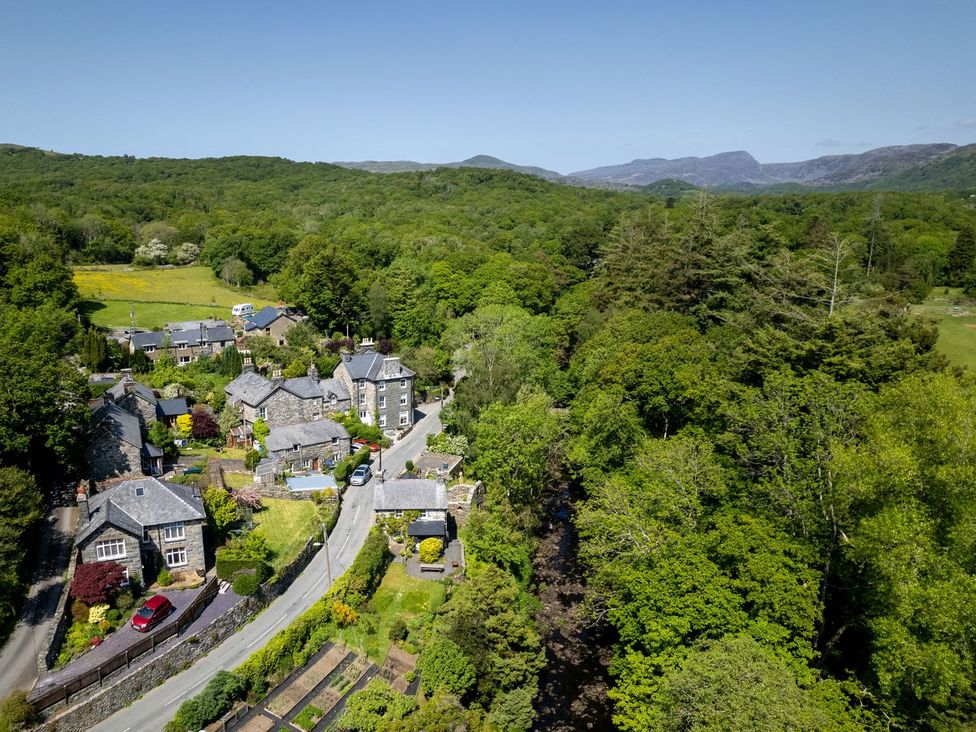 An aerial view of houses and trees in a rural area near Gwynfryn House in Llanbedr