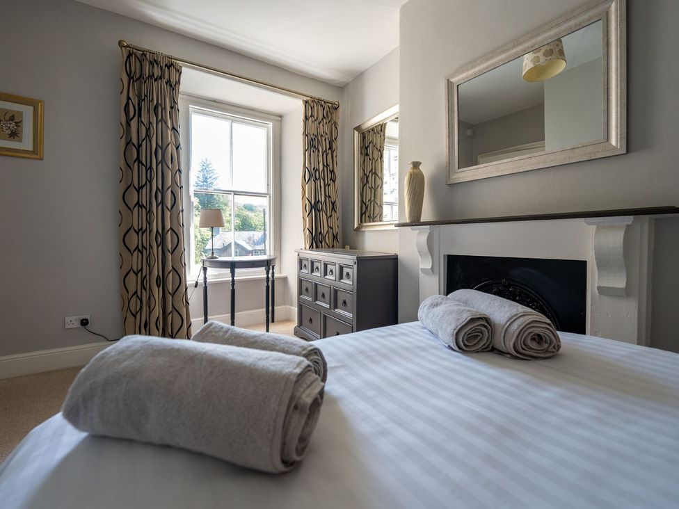 A bedroom with a bed, towels, and a chest of drawers at Gwynfryn House in Llanbedr