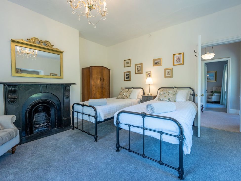 A bedroom with two beds and a fireplace at Gwynfryn House in Llanbedr