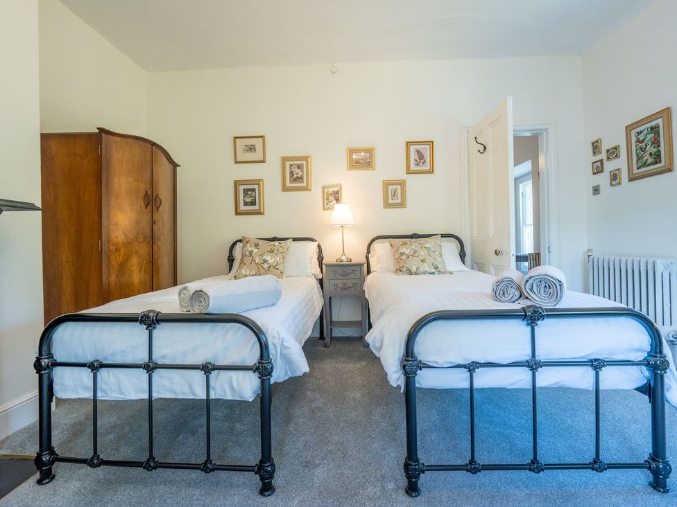 A bedroom with two beds and a wardrobe at Gwynfryn House in Llanbedr