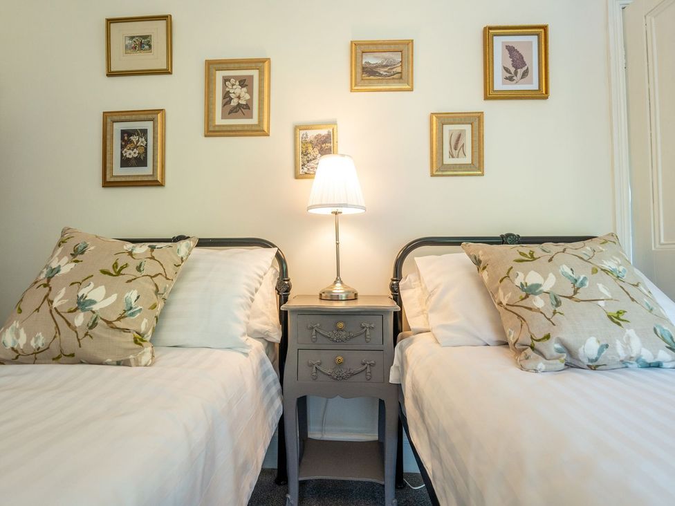 A bedroom with two beds and framed pictures on the wall at Gwynfryn House in Llanbedr