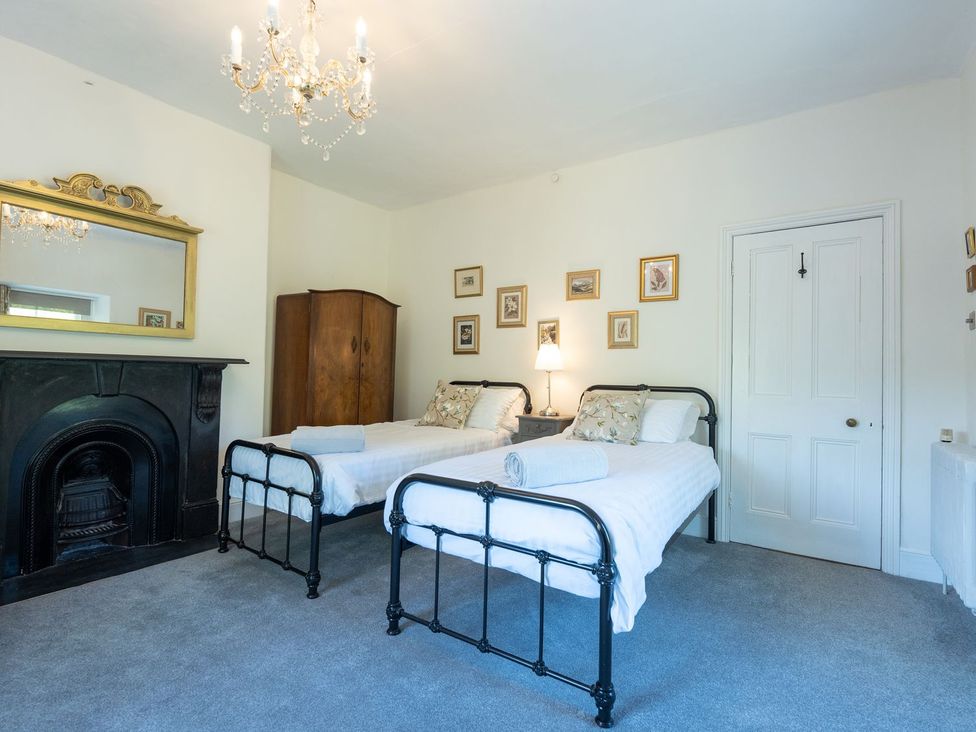 A bedroom with two beds and a fireplace at Gwynfryn House in Llanbedr