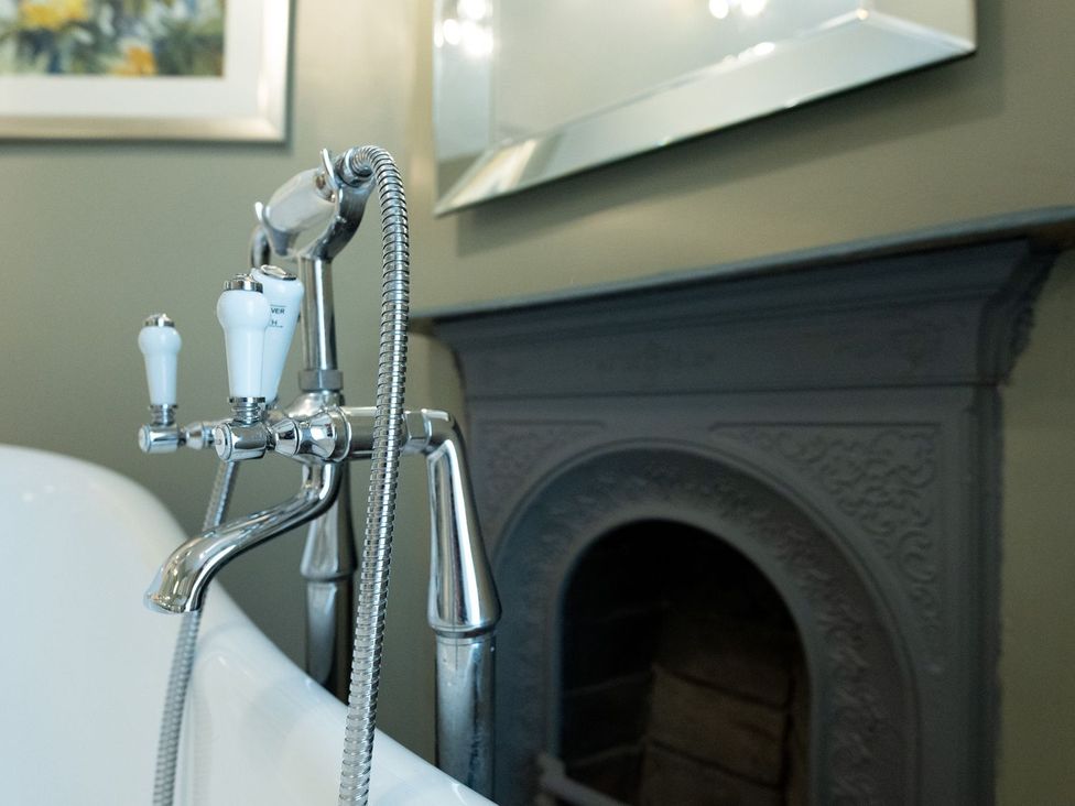 A bathtub with a faucet and a mirror in Gwynfryn House Llanbedr
