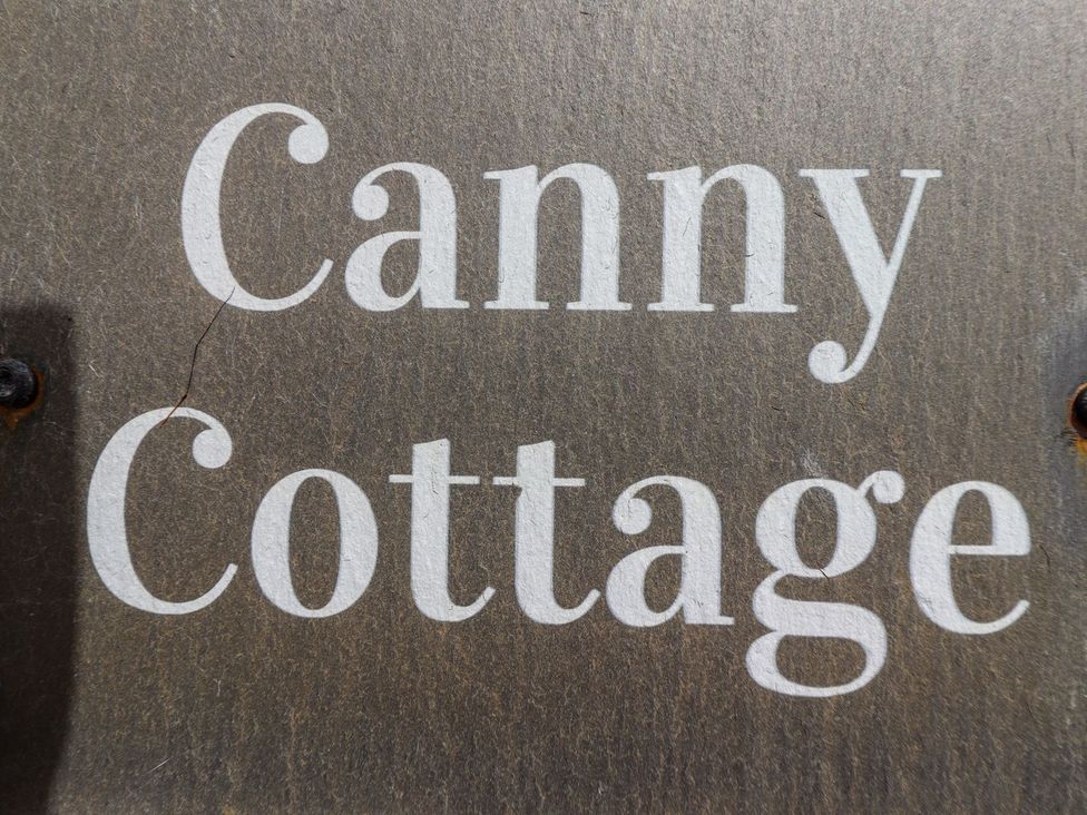 A wooden sign with the text Canny Cottage