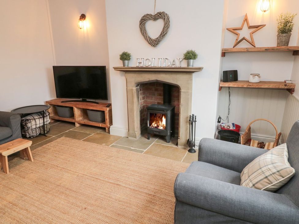 A living room with a fireplace and television at Canny Cottage in Belford