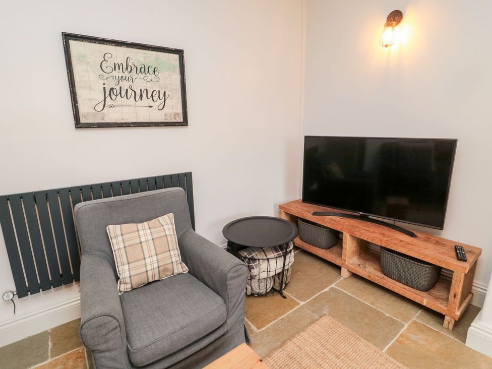 A living room with a chair and television at Canny Cottage in Belford