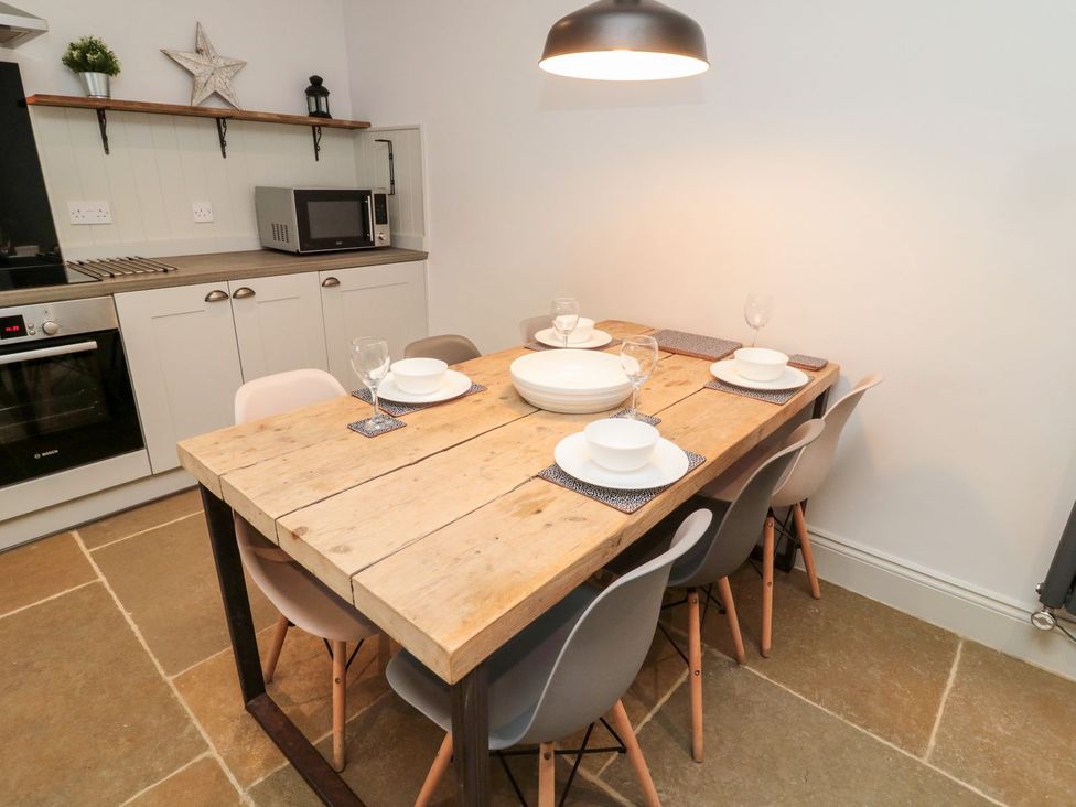 A dining room with a wooden table and chairs at Canny Cottage in Belford