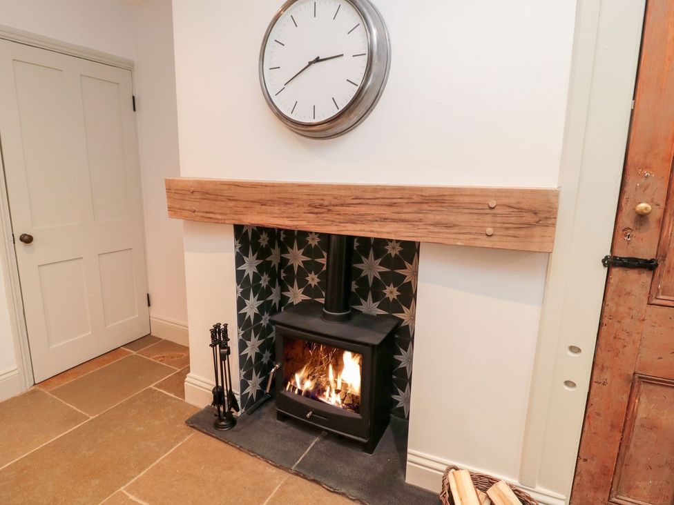 A fireplace with a clock and a door at Canny Cottage in Belford