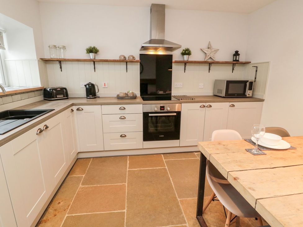 A kitchen with appliances and a dining table at Canny Cottage in Belford