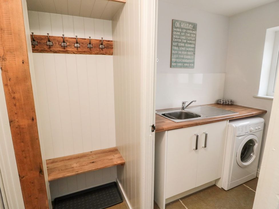 A utility room with a bench and washing machine at Canny Cottage in Belford