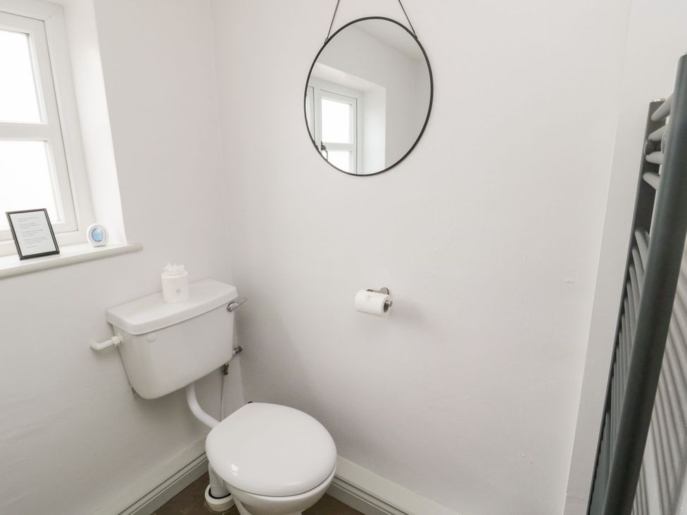 A bathroom with a toilet and mirror at Canny Cottage in Belford