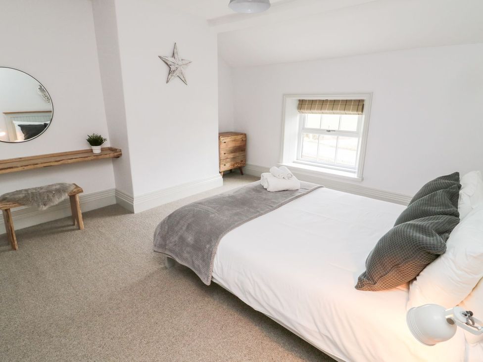 A bedroom with a bed and a mirror at Canny Cottage in Belford