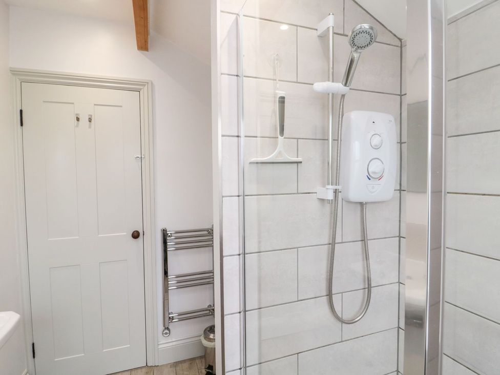 A shower area with a door and towel rail at Canny Cottage in Belford
