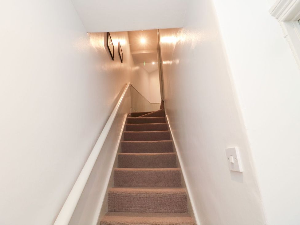 A staircase with a handrail leading to a hallway at Canny Cottage in Belford