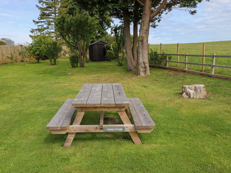 A picnic table in a garden at Canny Cottage in Belford