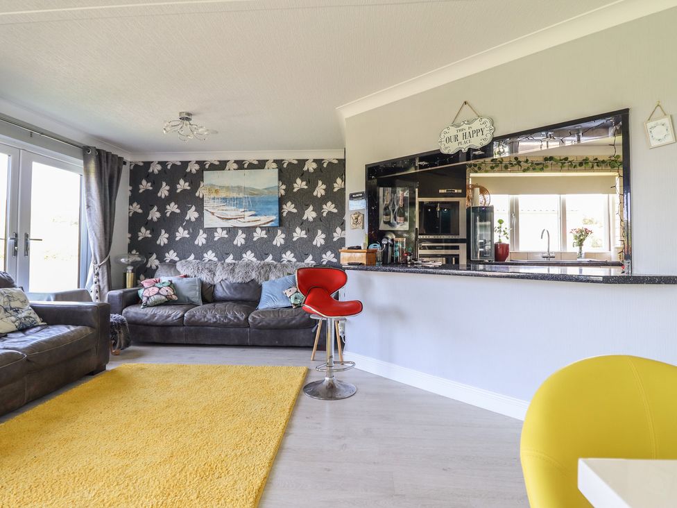 A living room with a sofa and a bar stool at Excalabur 10 in Morfa Bychan