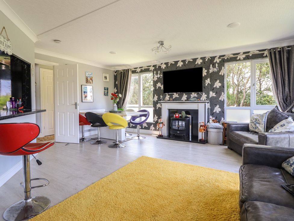 A living room with a fireplace and bar stools at Excalabur 10 Morfa Bychan