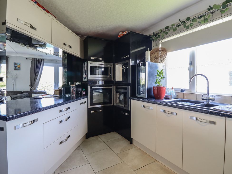 A kitchen with cabinets and appliances at Excalabur 10 in Morfa Bychan