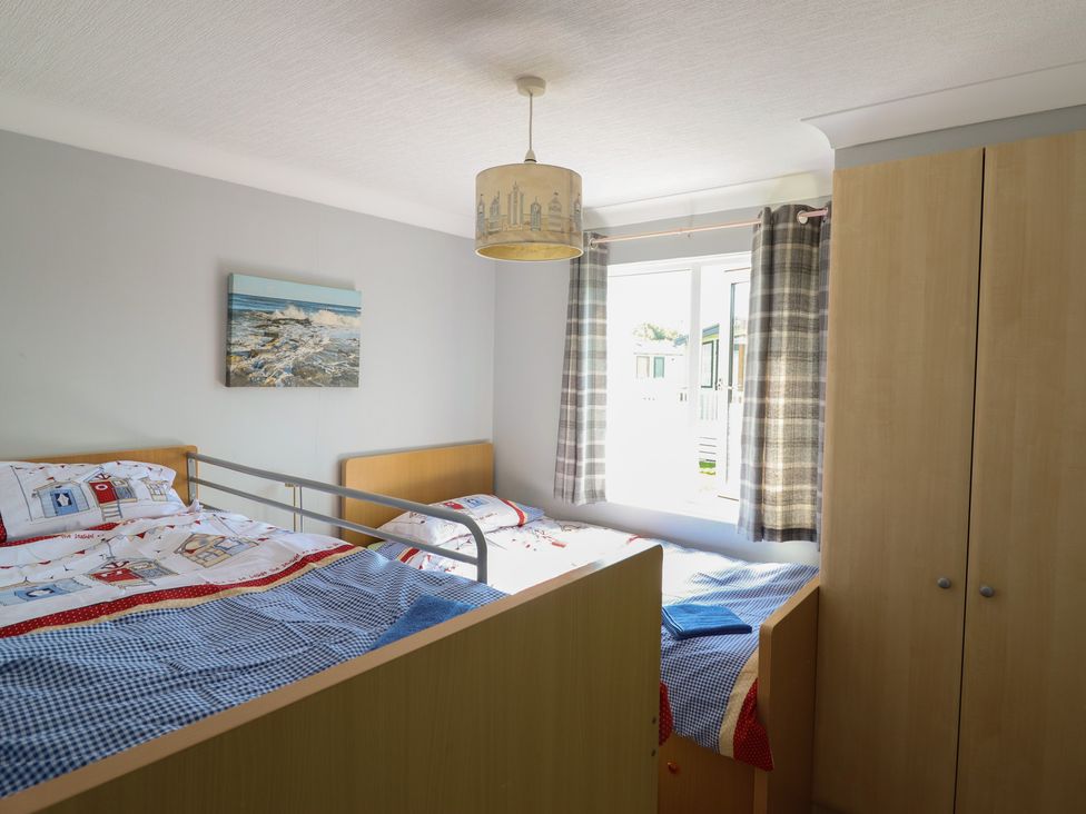 A bedroom with two beds and a wardrobe at Excalabur 10 in Morfa Bychan