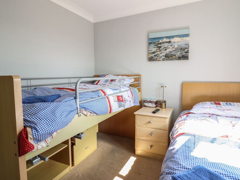 A bedroom with a bunk bed and single bed at Excalabur 10 in Morfa Bychan