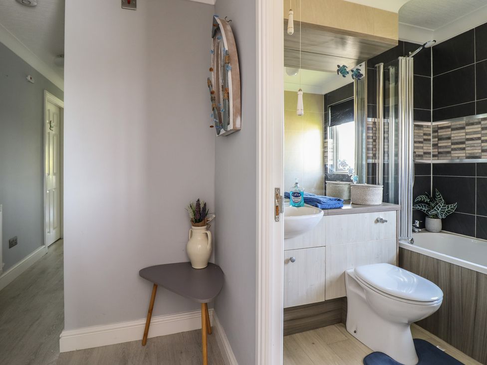 A bathroom with a bathtub, sink, and toilet at Excalabur 10 Morfa Bychan
