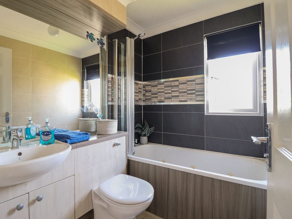 A bathroom with a bathtub, toilet, and sink at Excalabur 10 in Morfa Bychan