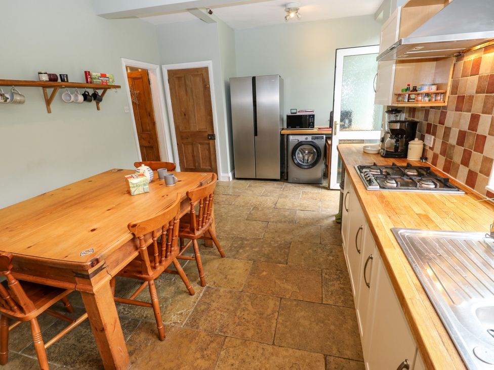 A kitchen with a table and chairs, appliances, and cabinets at Burras Hill in Otley