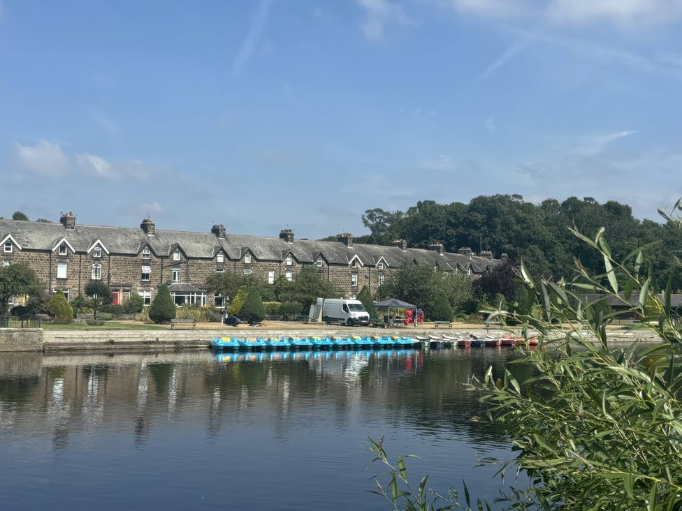 A row of houses with a river and parked boats at Burras Hill in Otley