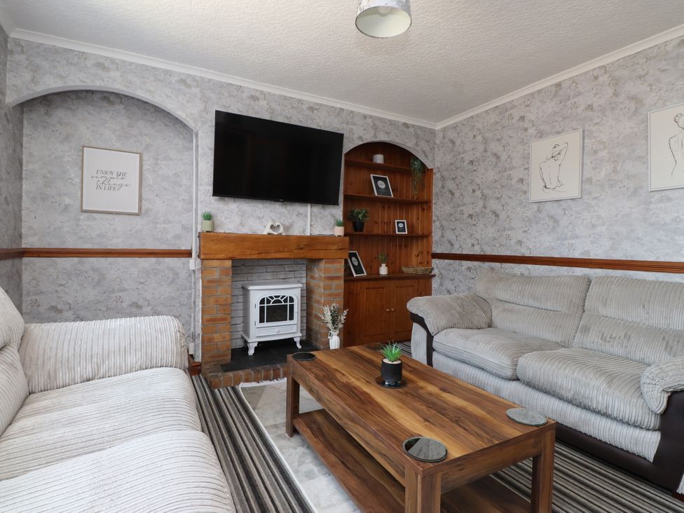 A living room with a fireplace and shelves at 31 Ffordd Y Maer Pwllheli