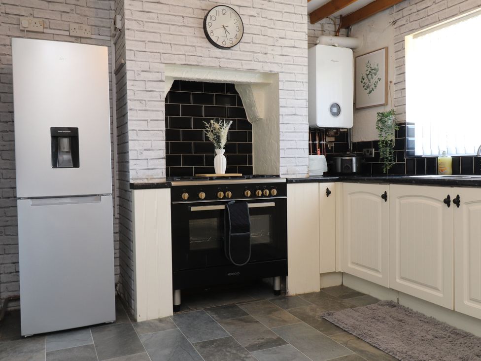 A kitchen with a refrigerator, oven and countertop at 31 Ffordd Y Maer in Pwllheli