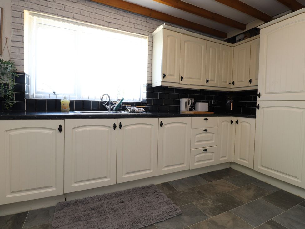 A kitchen with cabinets, sink and appliances at 31 Ffordd Y Maer in Pwllheli