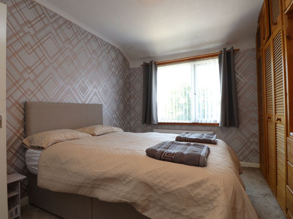 A bedroom with a bed, pillows, and a wardrobe at 31 Ffordd Y Maer, Pwllheli