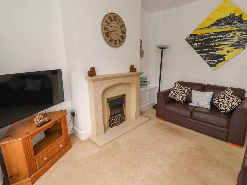 A living room with a fireplace and sofa at 19 Dunstan View in Seahouses