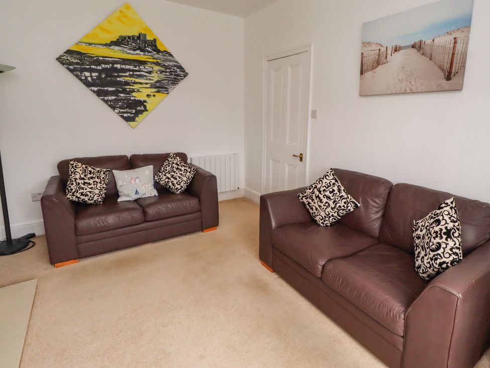 A living room with two sofas and wall art at 19 Dunstan View Seahouses