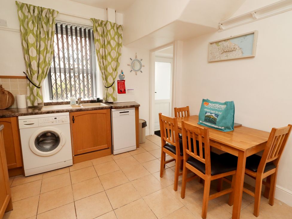 A kitchen with washing machine and table at 19 Dunstan View in Seahouses