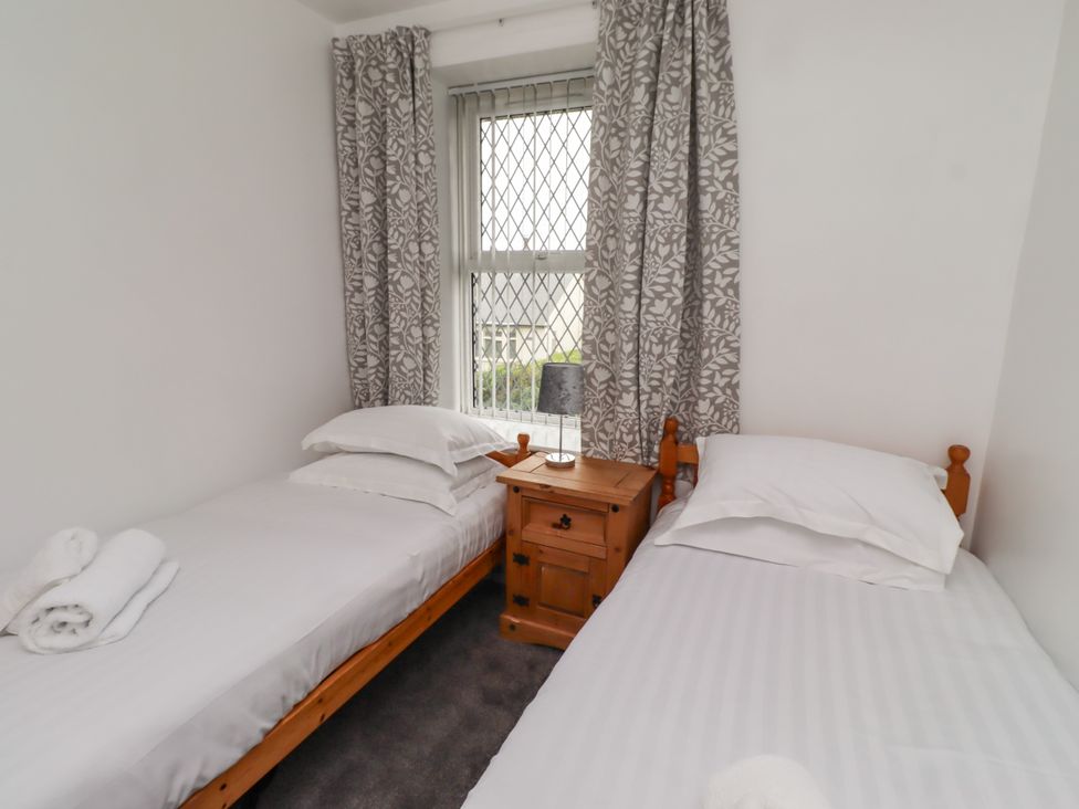 A bedroom with two single beds and a bedside table at 19 Dunstan View in Seahouses