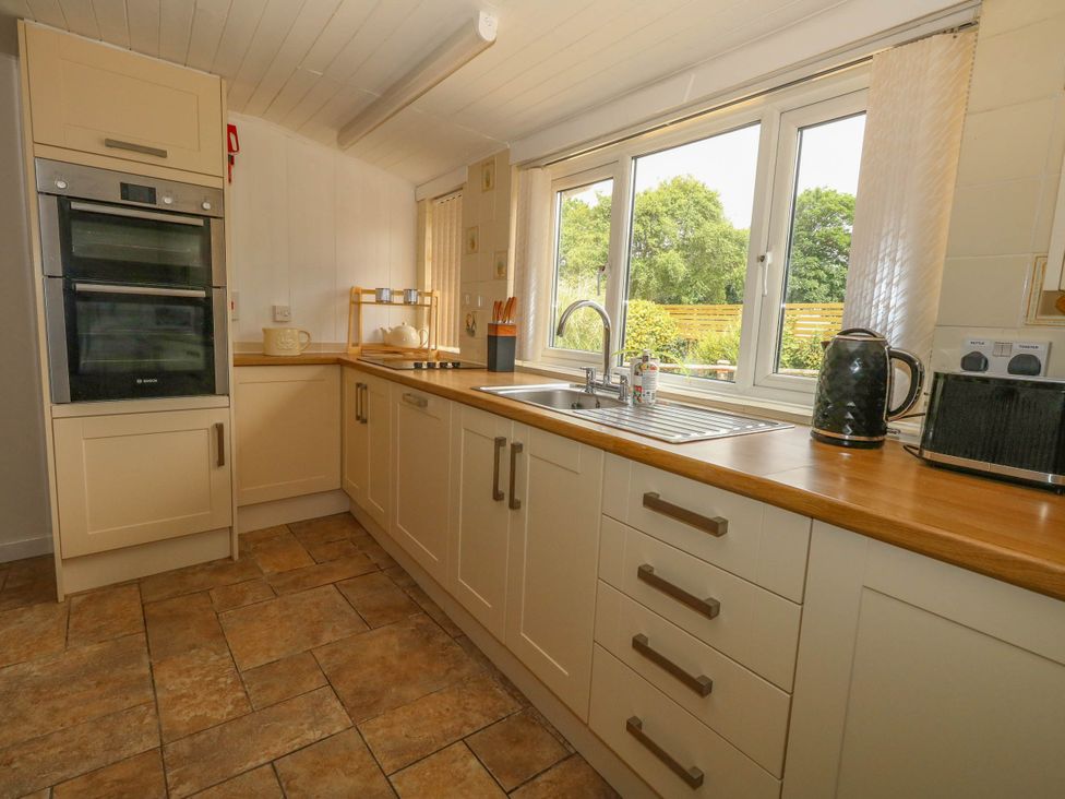 A kitchen with an oven, sink and counter at Greenwich Cottage in Burton Bradstock