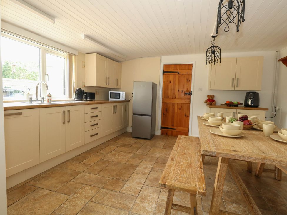 A kitchen with a table set for meals at Greenwich Cottage in Burton Bradstock